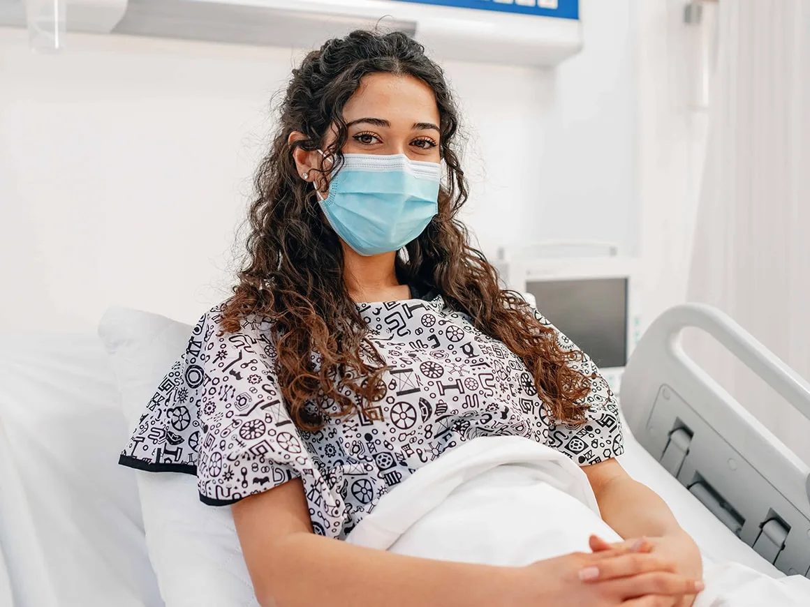 female patient lying in bed with mask on