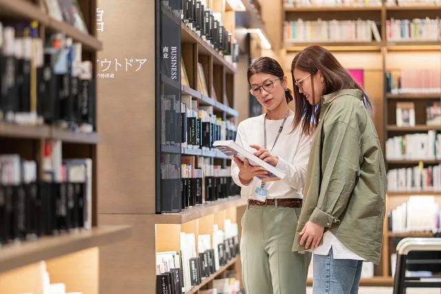 Librarian and student or researcher looking at a book in the library