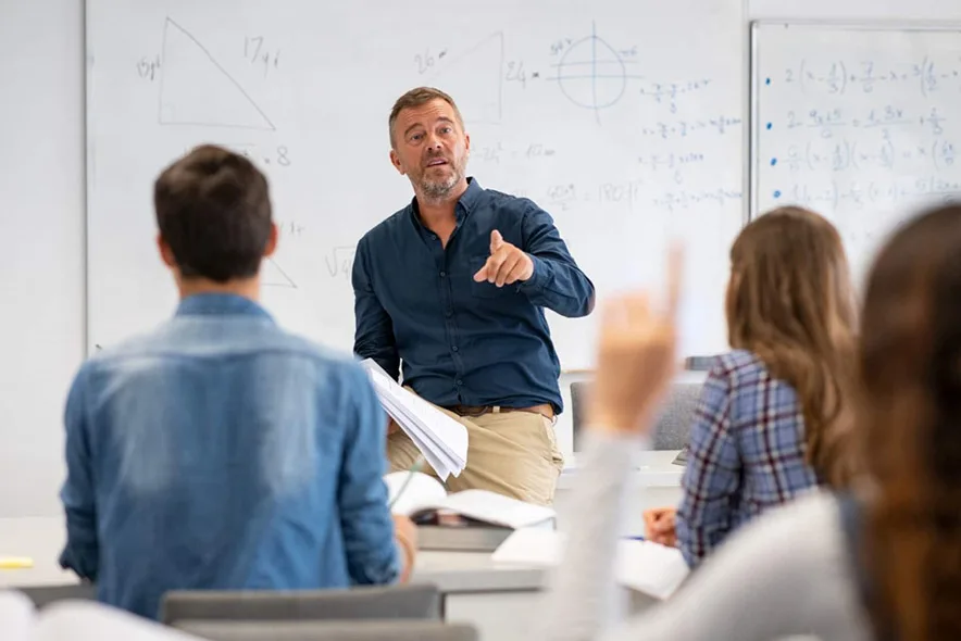 Teacher in front of a whiteboard explaining to students